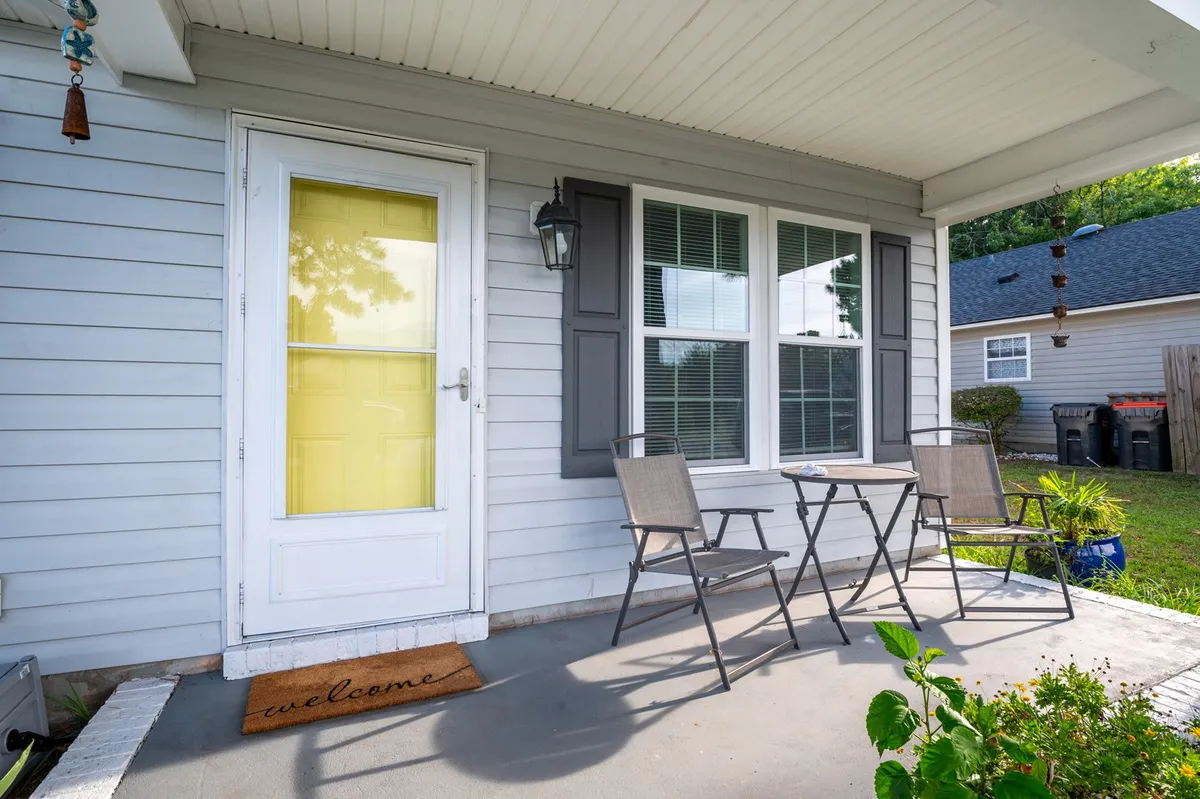 The photo features a welcoming patio scene with a yellow door, a small table and chairs, and a lantern, perfect for sipping coffee or relaxing. The atmosphere is inviting and hints at the transition between indoor dining and outdoor living.