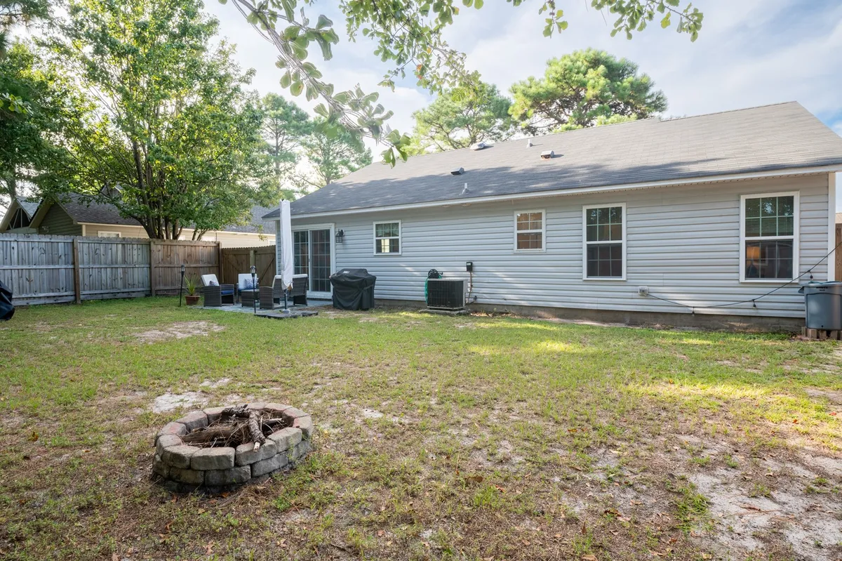 A cozy exterior seating area surrounding a fire pit, set in the backyard with a view of the house's rear. The setup invites families and pets to gather for outdoor meals, evening relaxation, or playtime, reinforcing the section’s focus on both daytime outings and comfortable returns home.