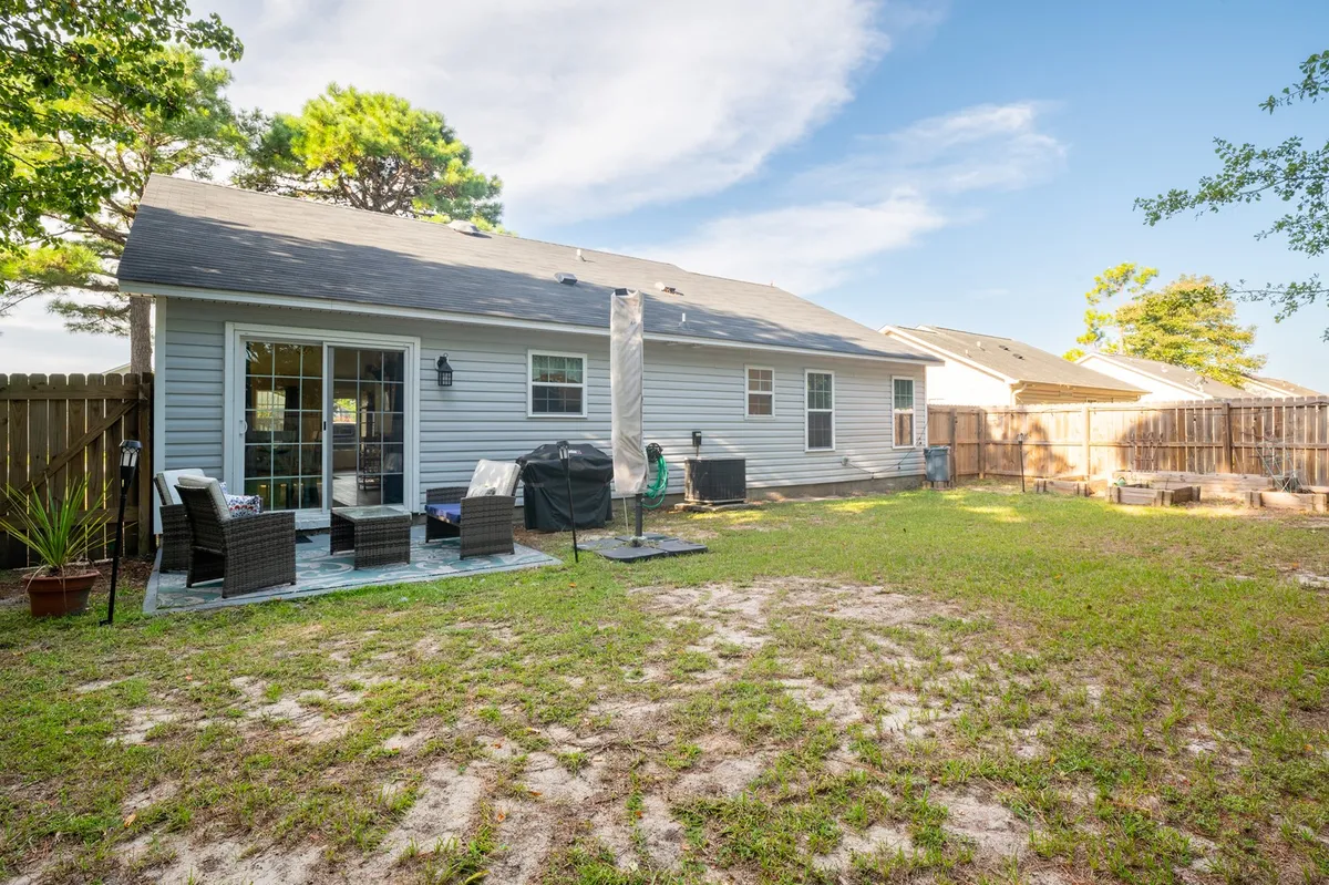 A relaxed backyard scene featuring patio furniture on a green lawn, surrounded by a fence. The space is ideal for outdoor gatherings and is secure for pets to roam, reflecting the backyard oasis mentioned in the section. The overall mood is comfortable and welcoming, perfect for both people and their four-legged companions.