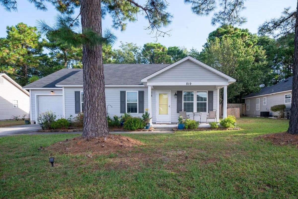 A welcoming ranch-style single-family house with a spacious front porch, lush green lawn, and large windows. The porch is inviting—perfect for relaxing or sipping coffee in the morning sun. The yard offers plenty of room for gatherings, pets, or enjoying a sunset in Wilmington’s mild coastal climate.