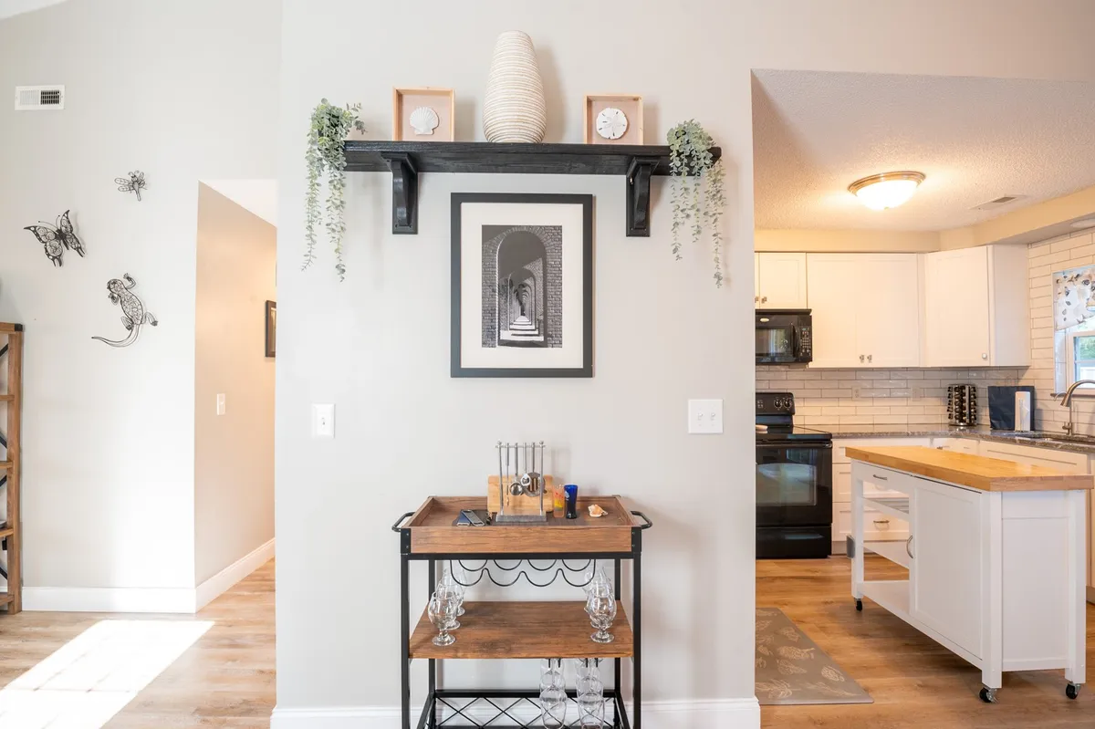 A welcoming living area featuring a shelf with nautical decor, framed artwork, and a stylish bar cart. The space feels open and comfortable, suggesting a spot where guests might gather, relax, or plan their day before venturing out to explore.