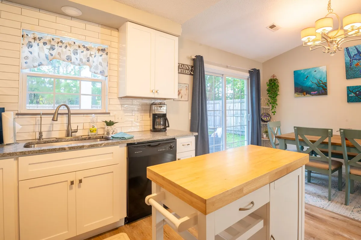 A bright, functional kitchen with an island countertop, kitchen sink, dining table, and eye-catching wall art. The space radiates warmth and utility, ideal for preparing meals with fresh seafood from local markets or assembling a picnic before heading to the beach.