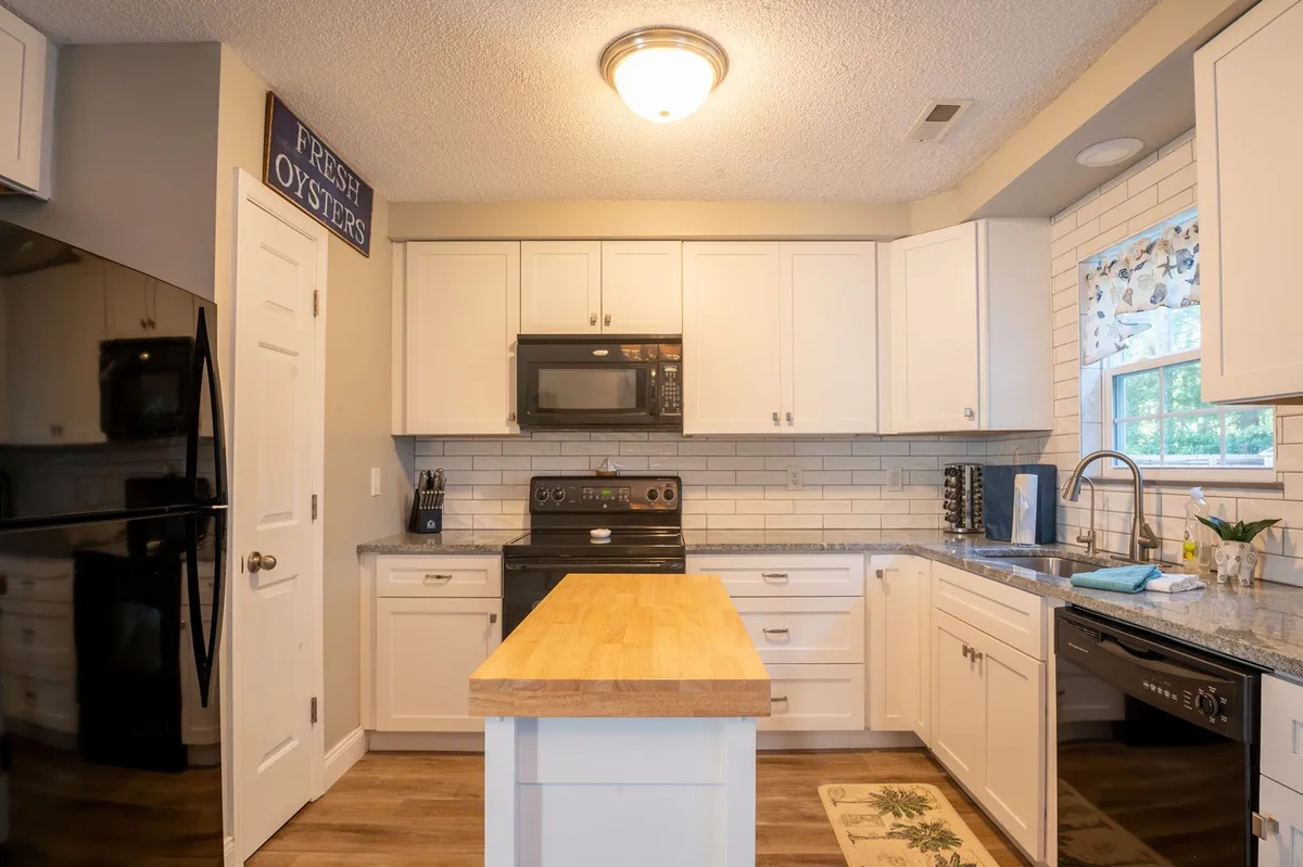 A modern and well-equipped kitchen featuring a central island, stainless steel appliances, granite countertops, and white cabinetry. The space is organized for both family cooking sessions and easy entertaining, embodying modern comfort and utility.