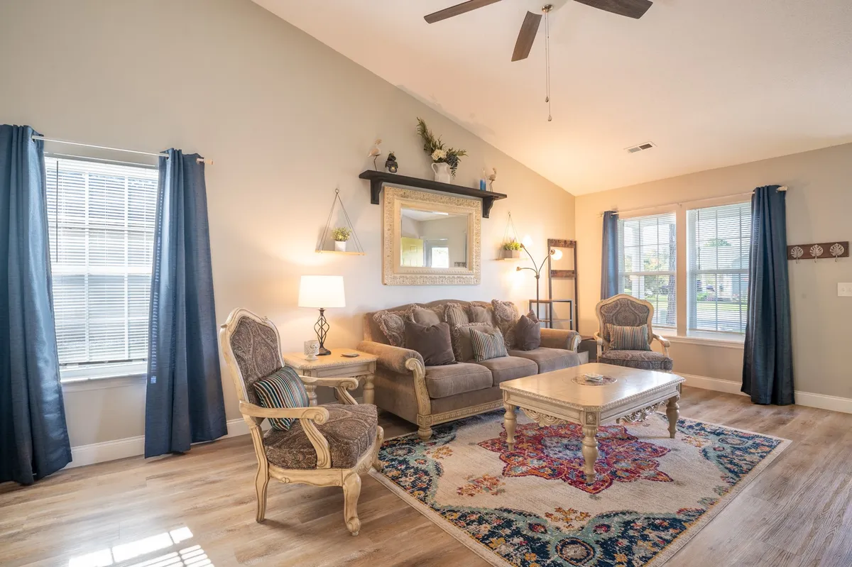 A comfortable living room featuring a sofa, coffee table, rug, mirror, and curtains. The space is inviting, ideal for relaxing after work, entertaining, or enjoying casual downtime.